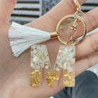 Llaveros Charms Personalizados con Iniciales - Letras Doradas y Borla Blanca para Bolsos